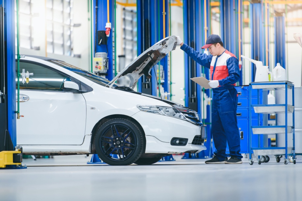 Car mechanic looking under car bonnet