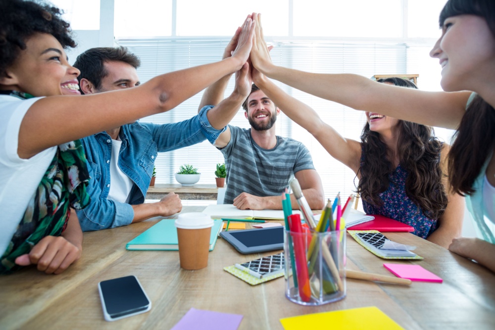 Group of colleagues putting their hands together over a table during a meeting