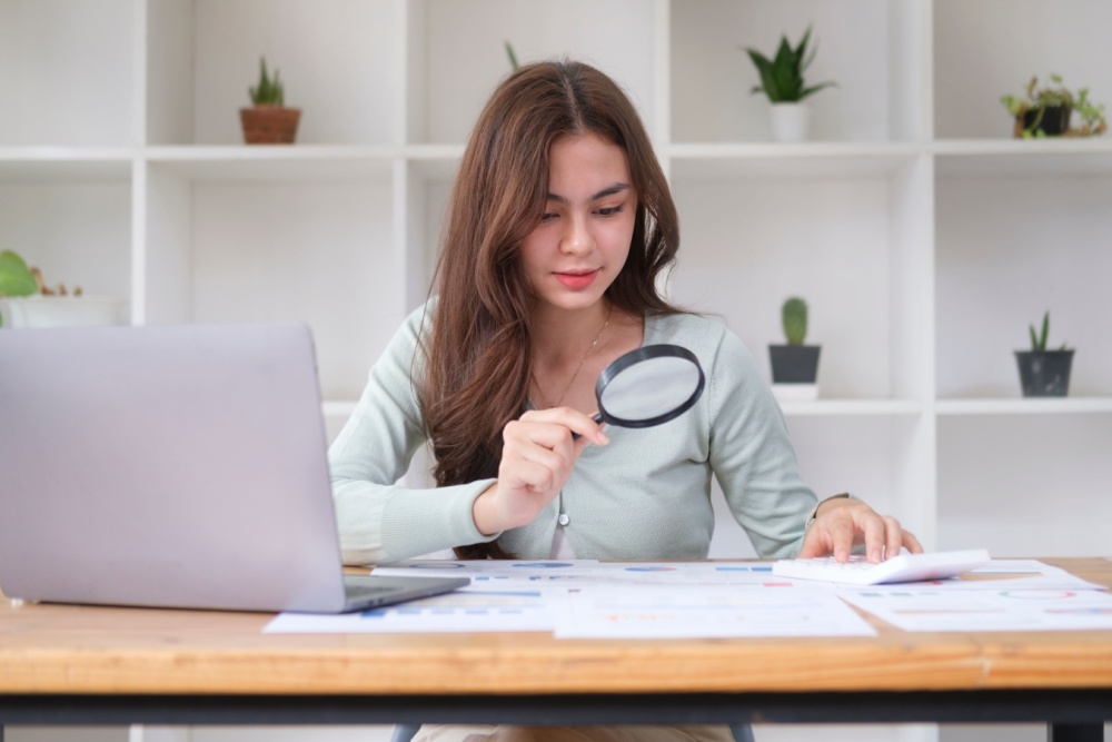 Women holding a magnifying glass to paperwork