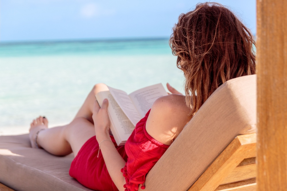Woman reading on a sun lounger at the beach